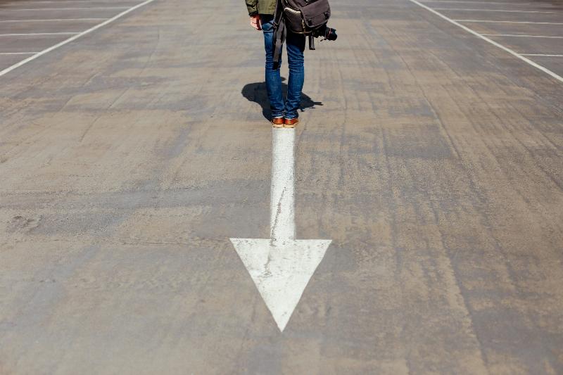 Arrow pointing backwards as someone stands on its edge