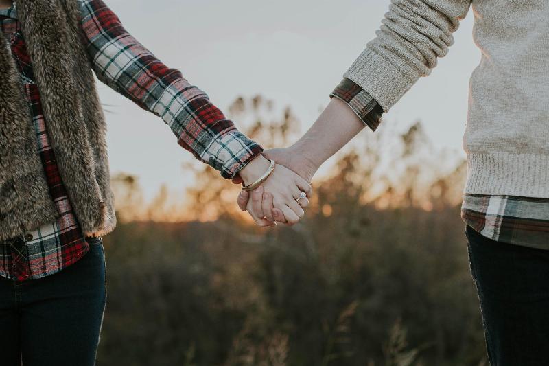 couple holds hands in a field