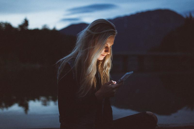 woman texting by the night lake