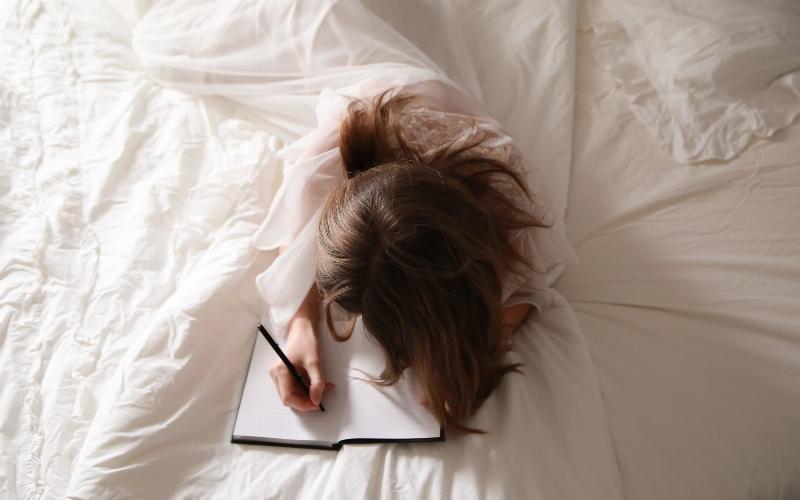 woman writing in her journal in bed