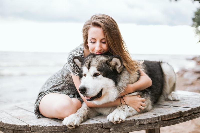 woman hugging dog on wooden table