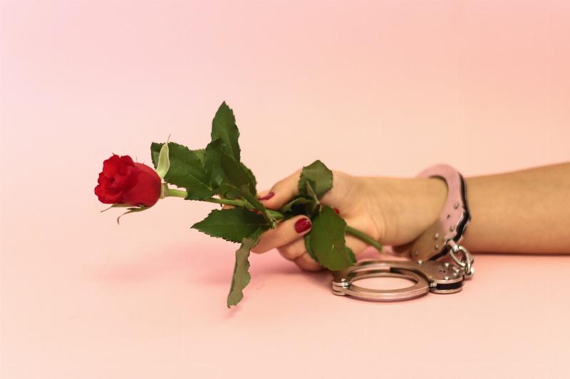 woman with handcuffed hand holding a rose