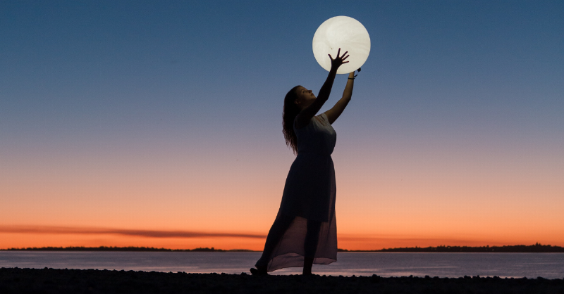 woman reaches up to the moon