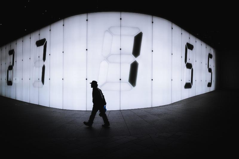 man walking past giant passing clock