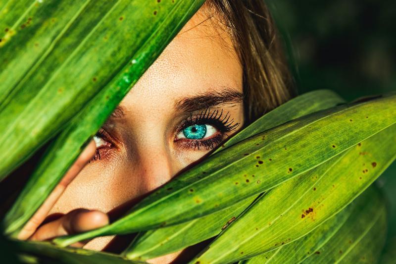 woman with blue eyes looking through leafs
