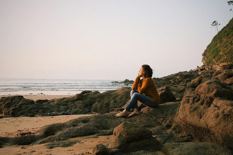 woman sitting on the shore in jeans