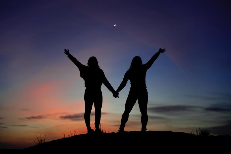 two silhouettes holding hands by the moon's light