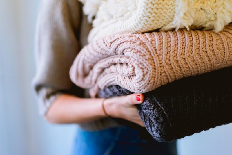 woman holding folded sweaters