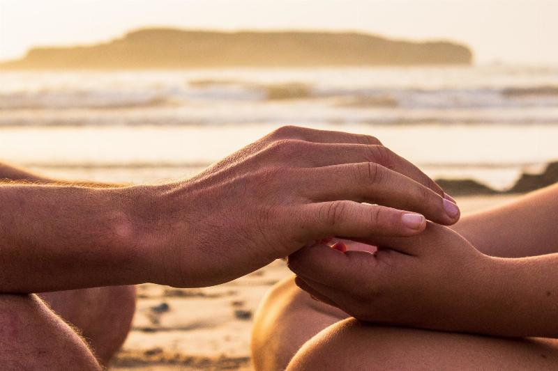 two hands holding at the beach
