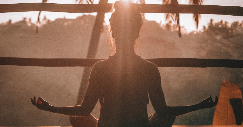 woman practicing yoga sitting in sunset