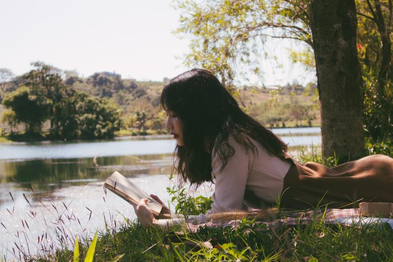 woman reading in the park laying down on the grass