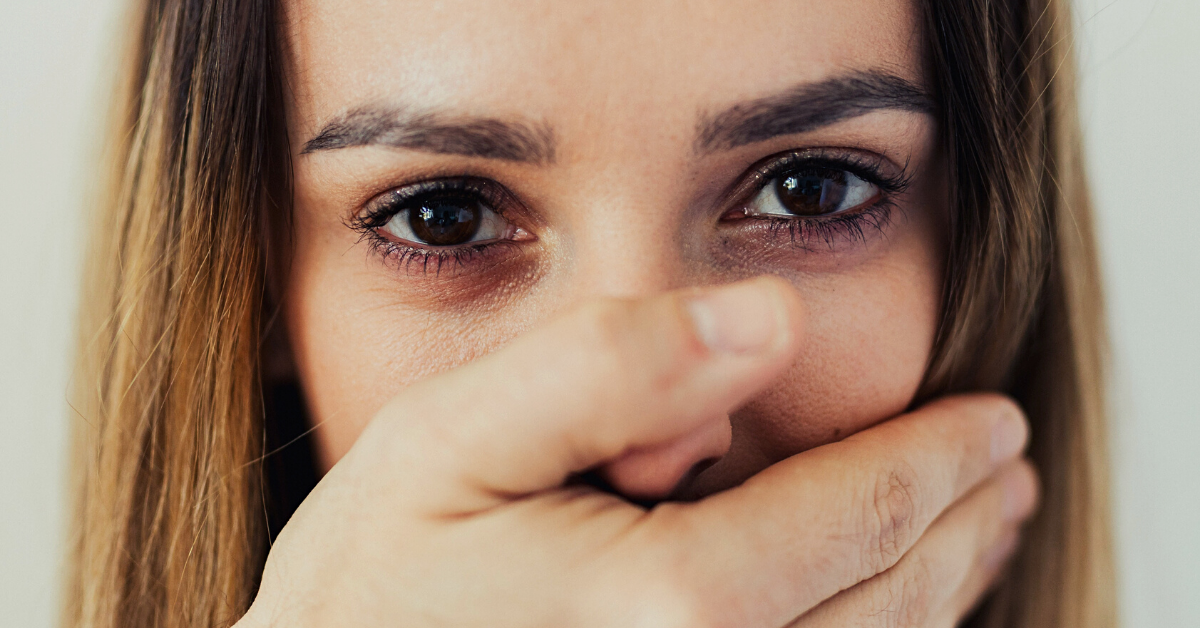 man holds his hand up to woman's mouth