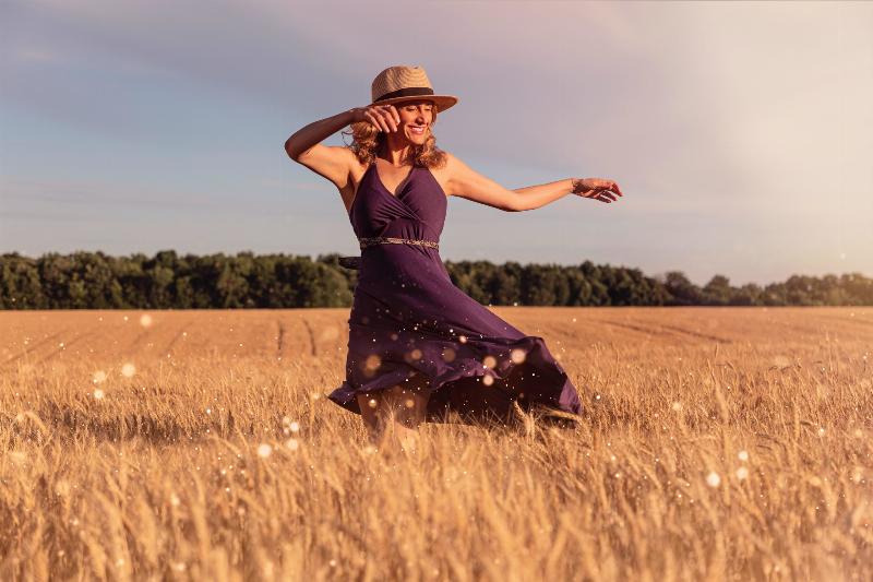 woman dancing in a field with fedora hat