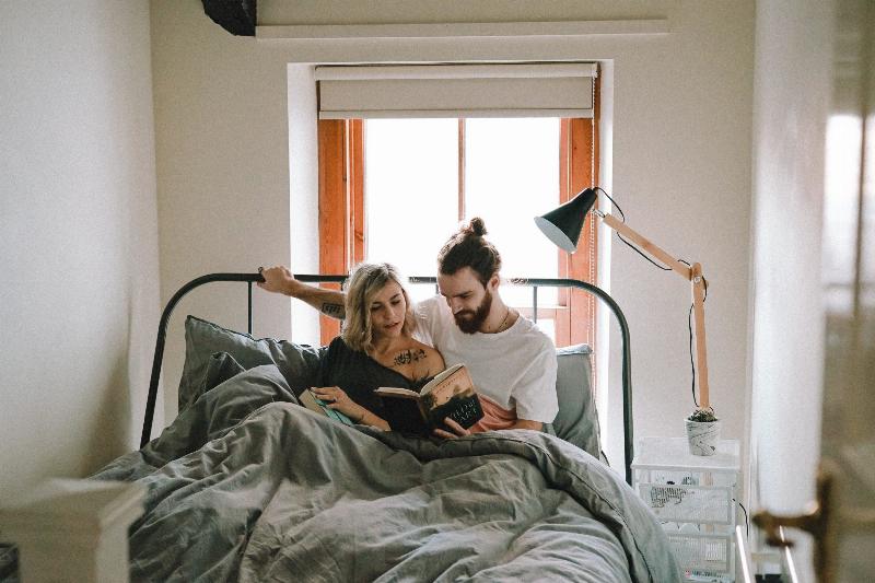 man and woman reading a book in bed