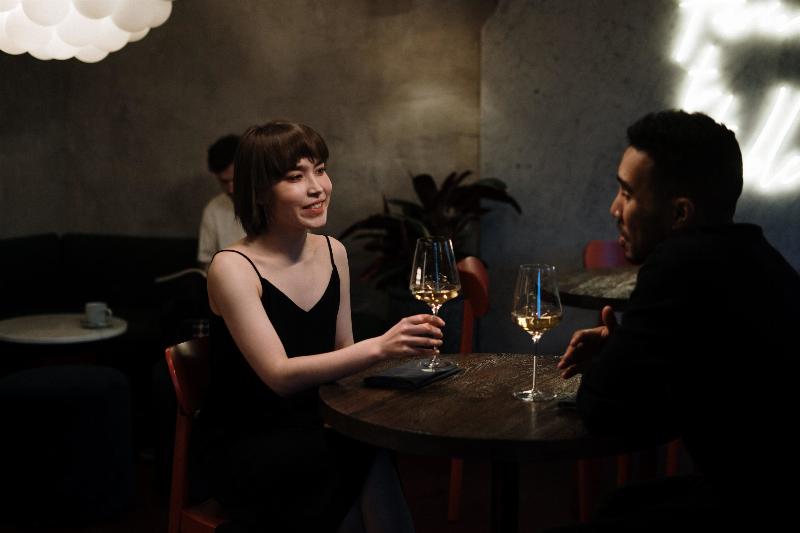 man and woman sit at table with wine talking