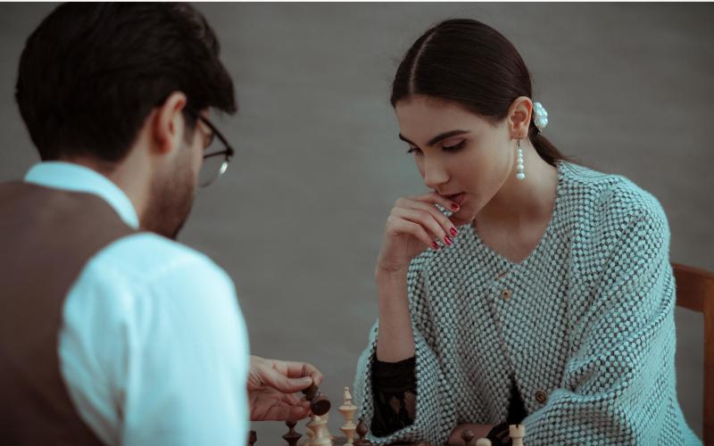 woman and man play a game of Chess