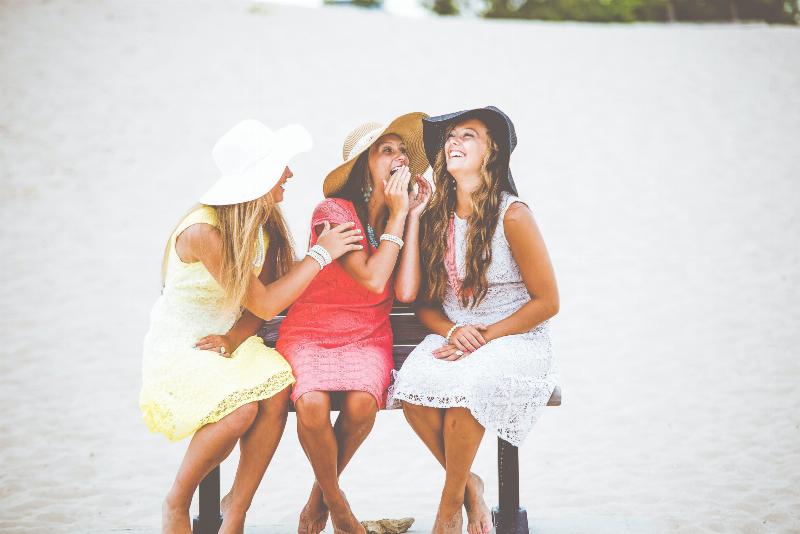 three women whispering gossip while sitting on bench