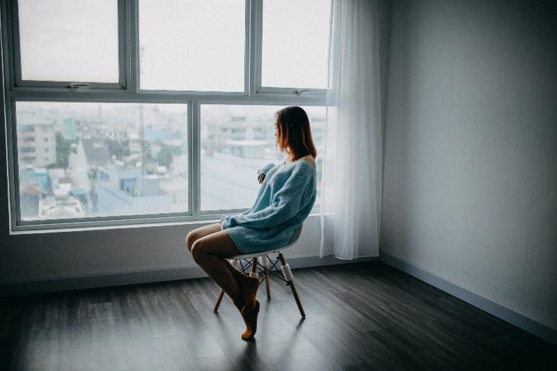 girl sits by the window looking out