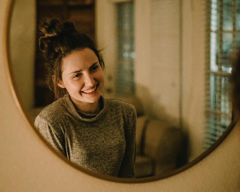 woman smiling at her mirror reflection