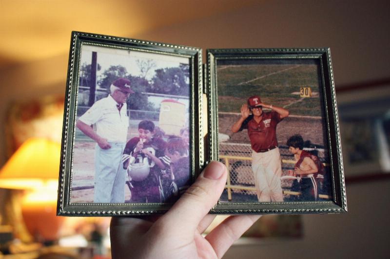 hand holds photo fame of kid and old man at baseball games
