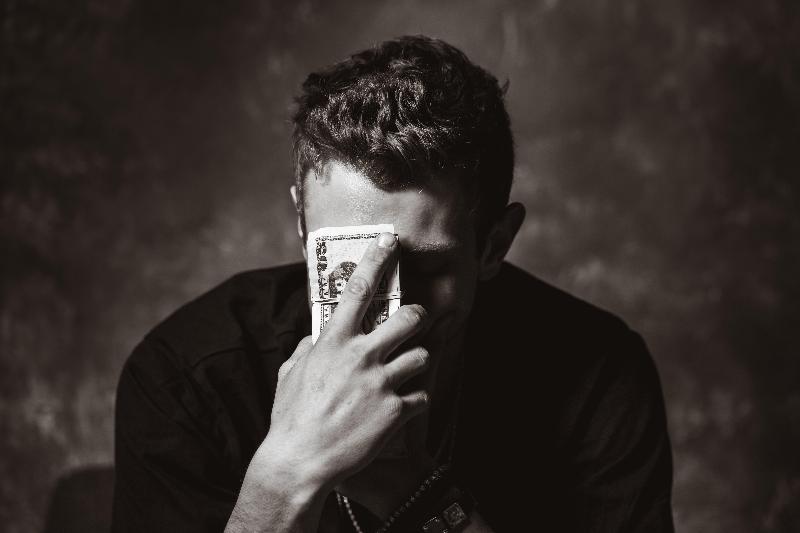 black and white photo of man holding up cash to his face and with his eyes closed