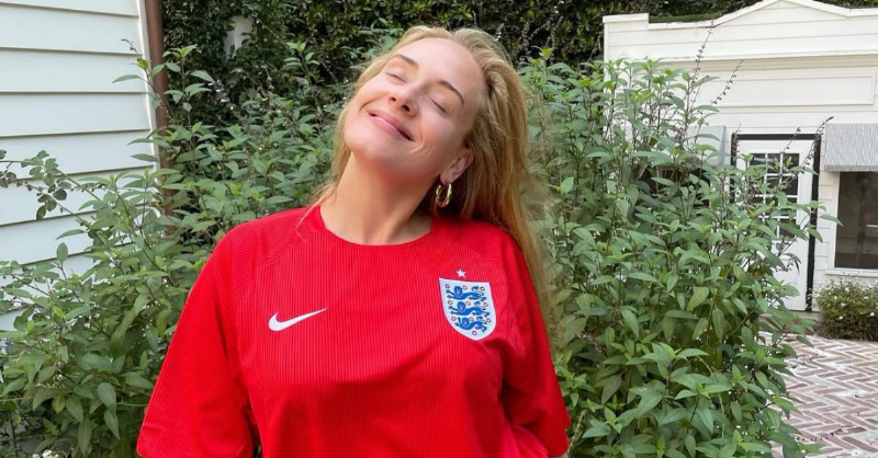 Adele smiles with her eyes closed in football jersey