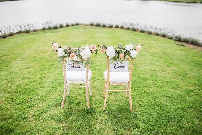 bride and groom chair on lawn by water