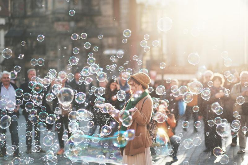 woman blowing bubbles on the street and surrounded with them