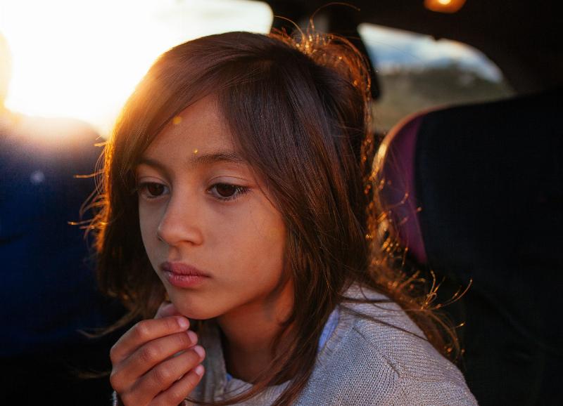 little girl looks lost in thought by the sun