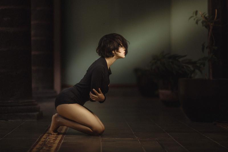 woman hugging he stomach while kneeling forward