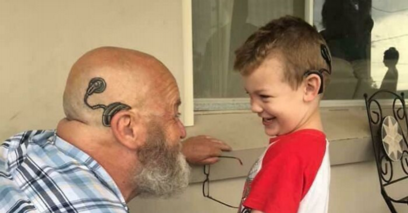 grandpa kneels and smiles at toddler who smiles back