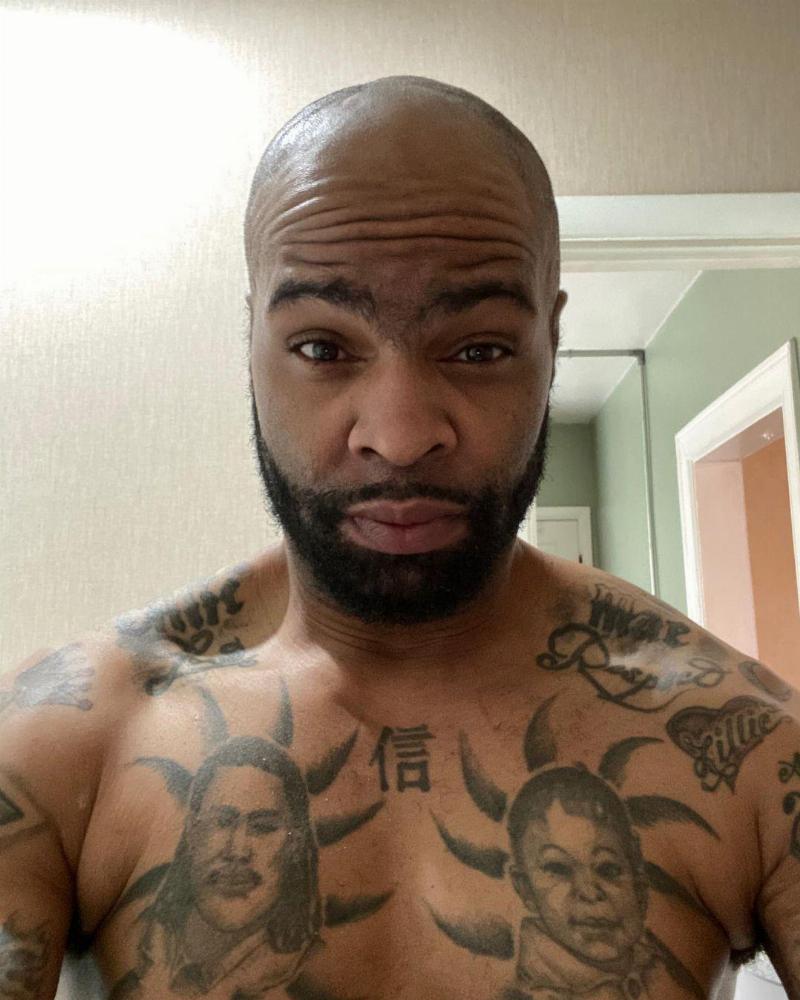 Bear's shirtless selfie covered in tattoos and smirking