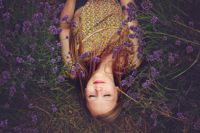 woman lays on bed of flowers in the grass