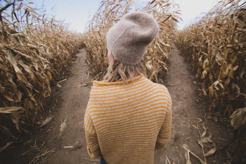 woman stands by corn maze entrance with two paths