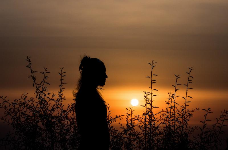 woman standing by sunset as a silhouette