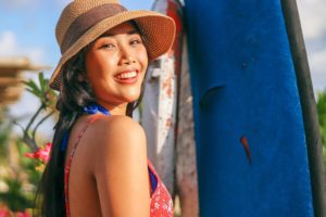 woman smiles in red sun dress while wearing sunhat outside
