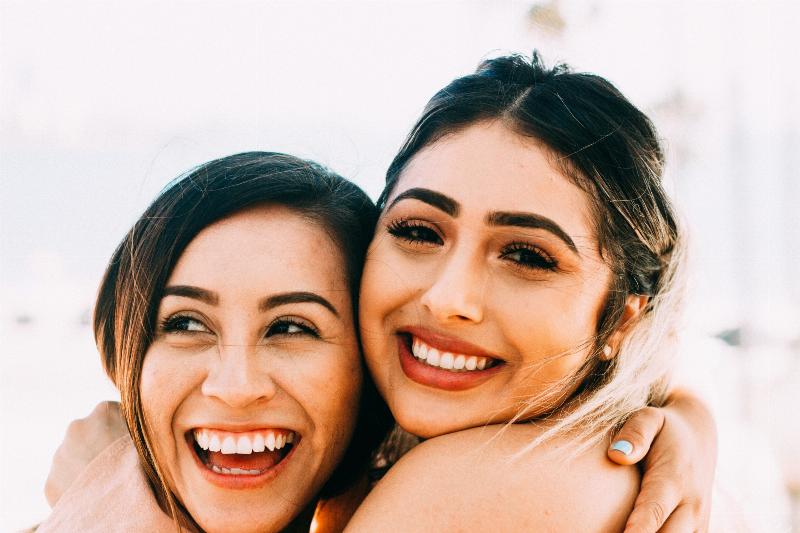 close up of two women hugging and smile it
