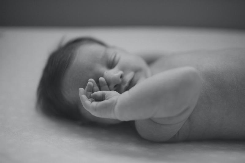 black and white photo fo new born baby rubbing their eye