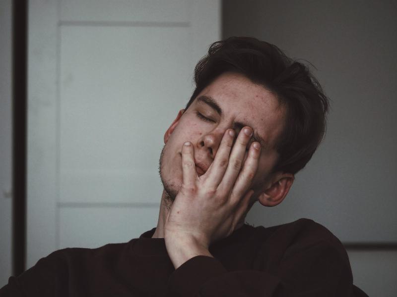 man hiding his face with his hand looking upset