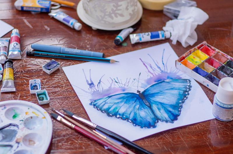 drawing of butterfly around paint on table