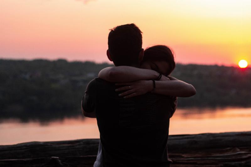 woman hugs man by sunset water