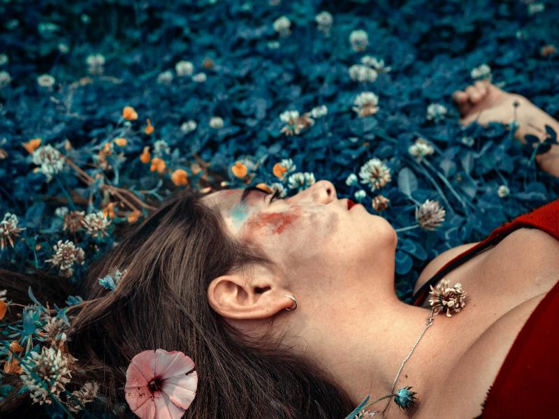 woman laying in bed of flowers with paint