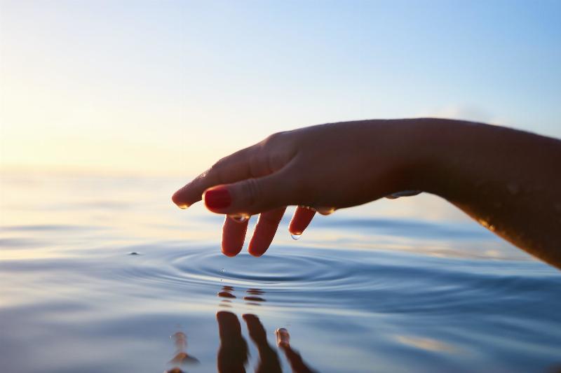 hand touching water  in the sun
