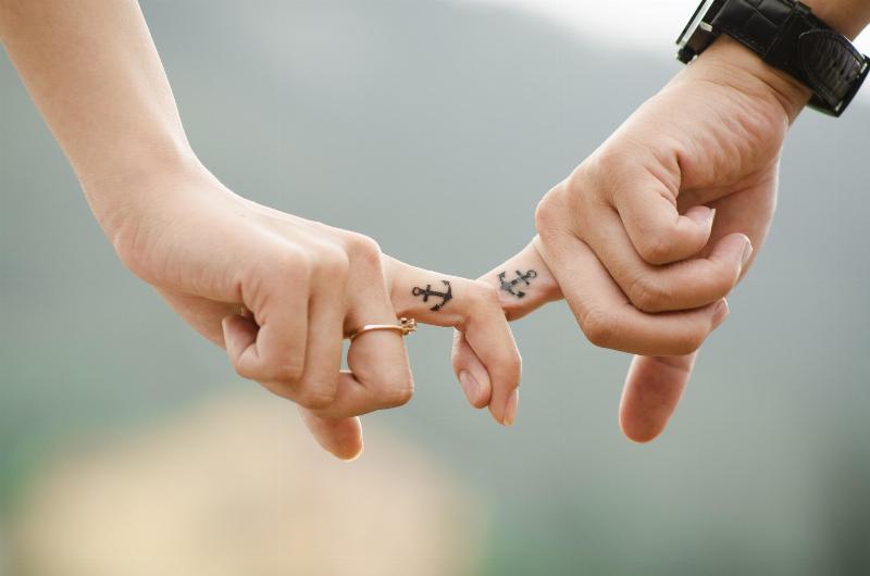two people with anchor tattoos on their fingers link fingers