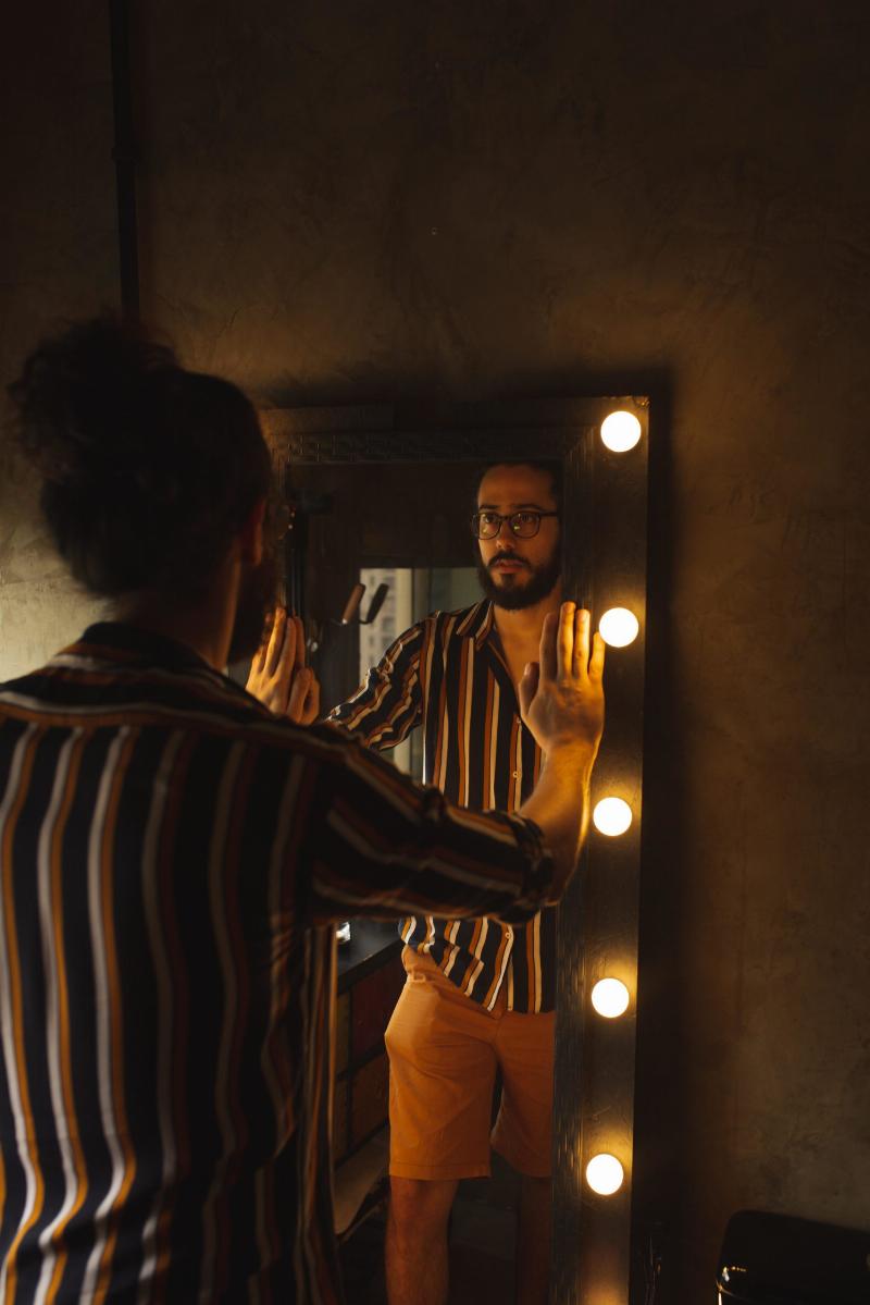 man looking in lit mirror