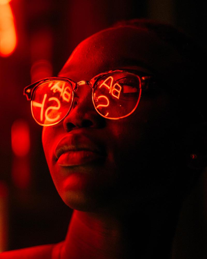 woman wearing glasses that reflect red neon light