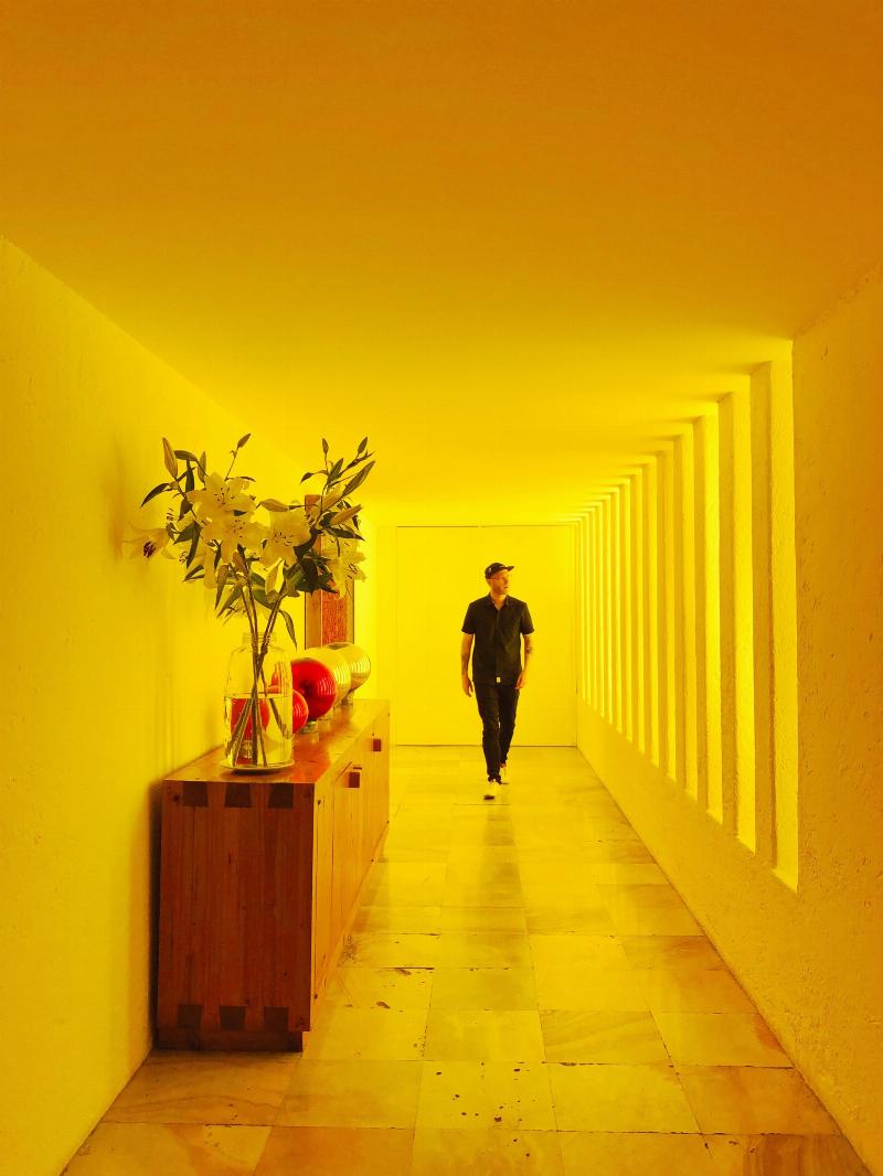 man walking in yellow lit hallway