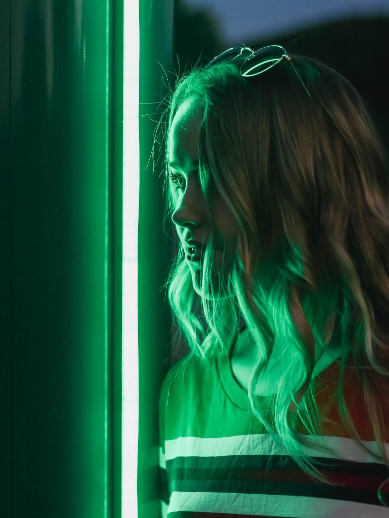 woman standing in the reflection of green neon lights