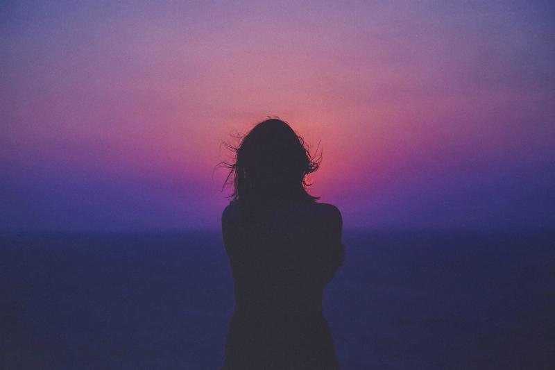 silhouette of a woman by purple sunrise