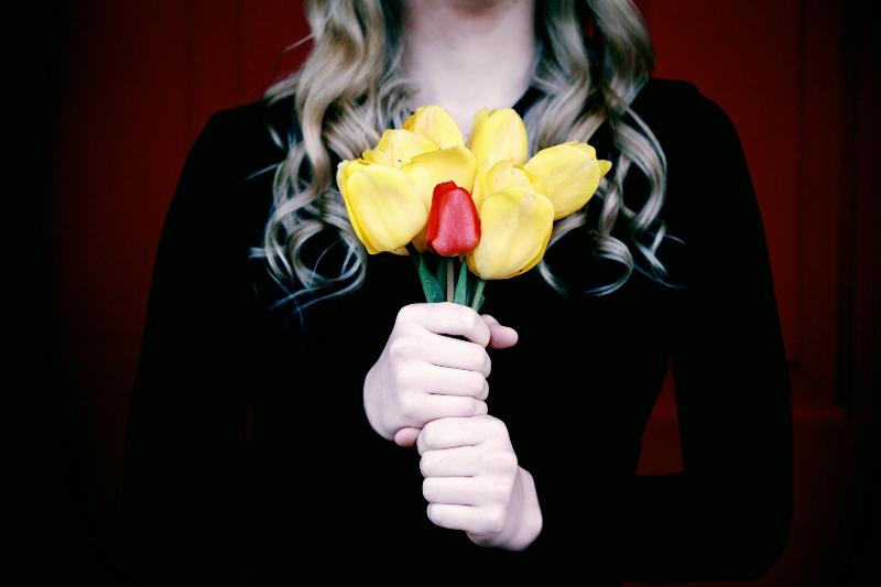 Women holding up bouquet of yellow and red tulips